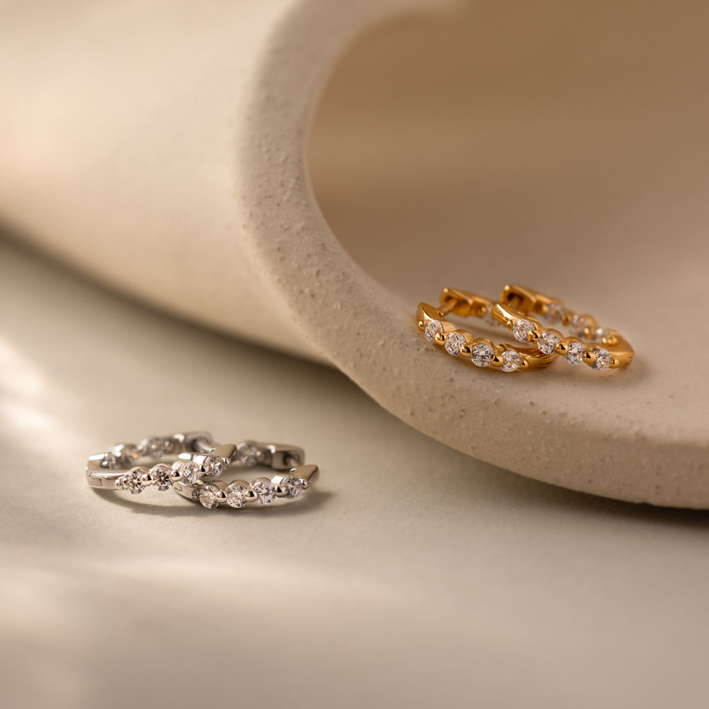 Two pairs of Mini Diamond Beaded Huggies in silver and gold, these modern gemstone-studded earrings are shown on a neutral background.
