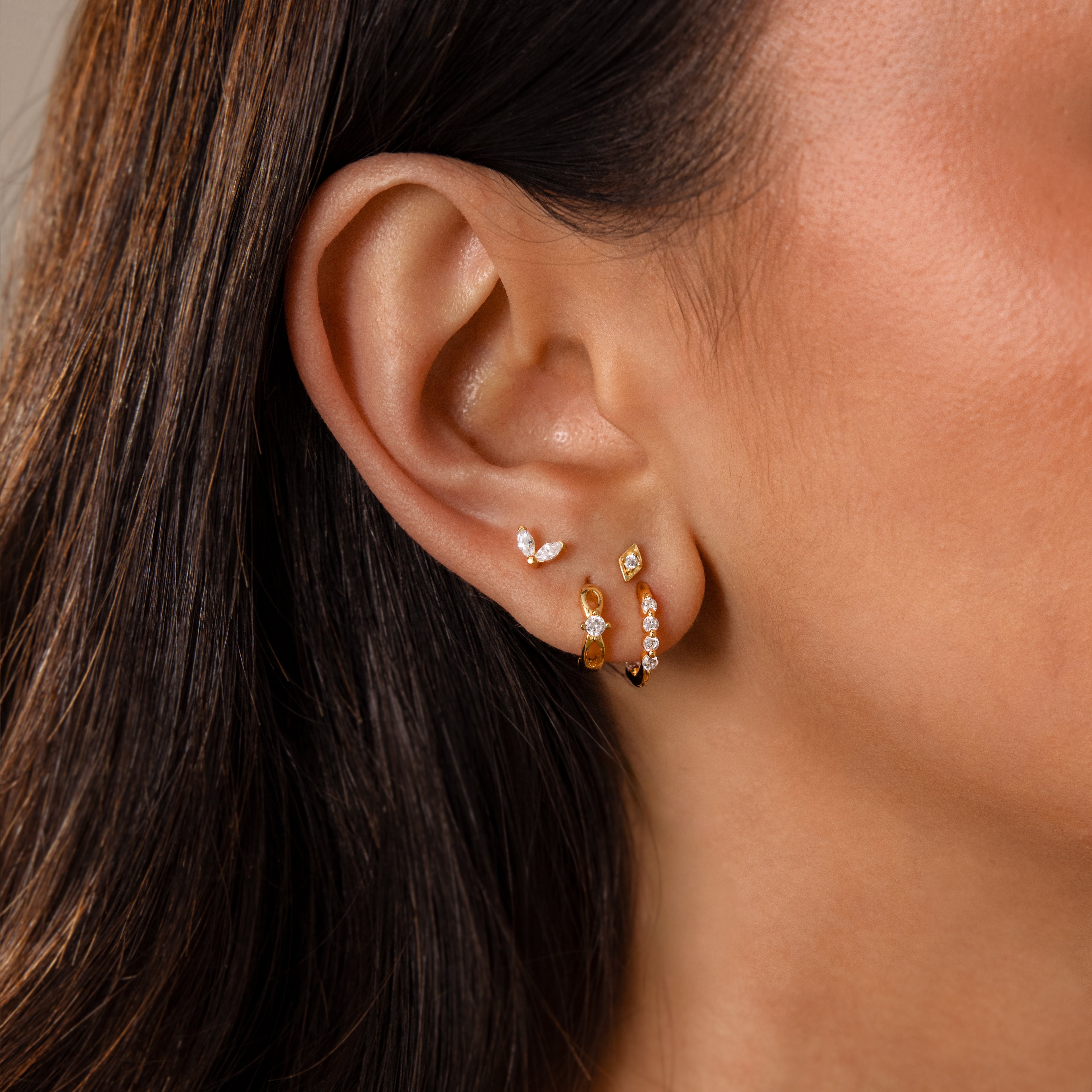 Close-up of a womans ear wearing Mini Diamond Beaded Huggies—modern huggie earrings featuring gemstone beads in unique shapes and sizes.
