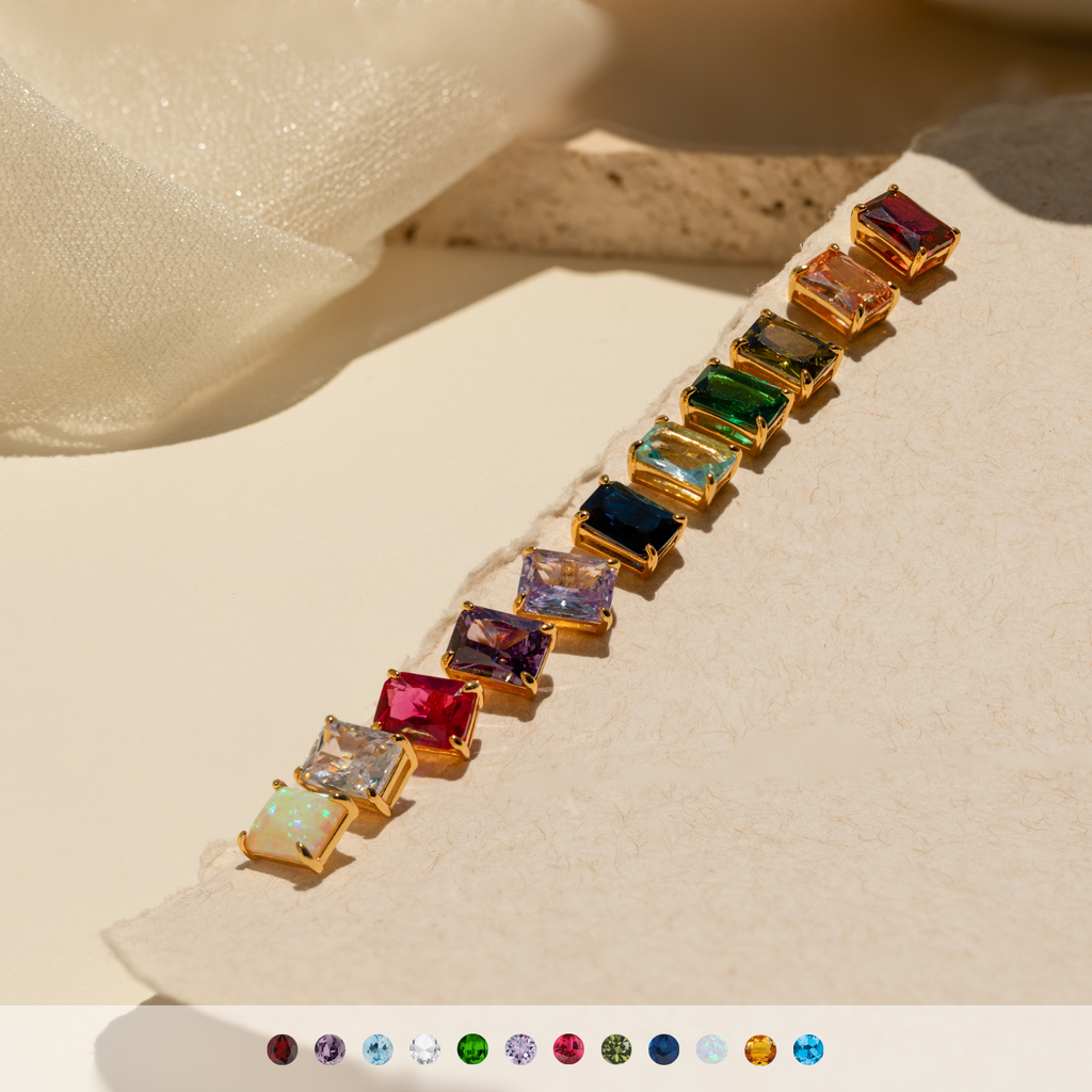 Emerald Birthstone Studs, ideal for personalized gifts, are displayed on a textured beige surface in sunlight.