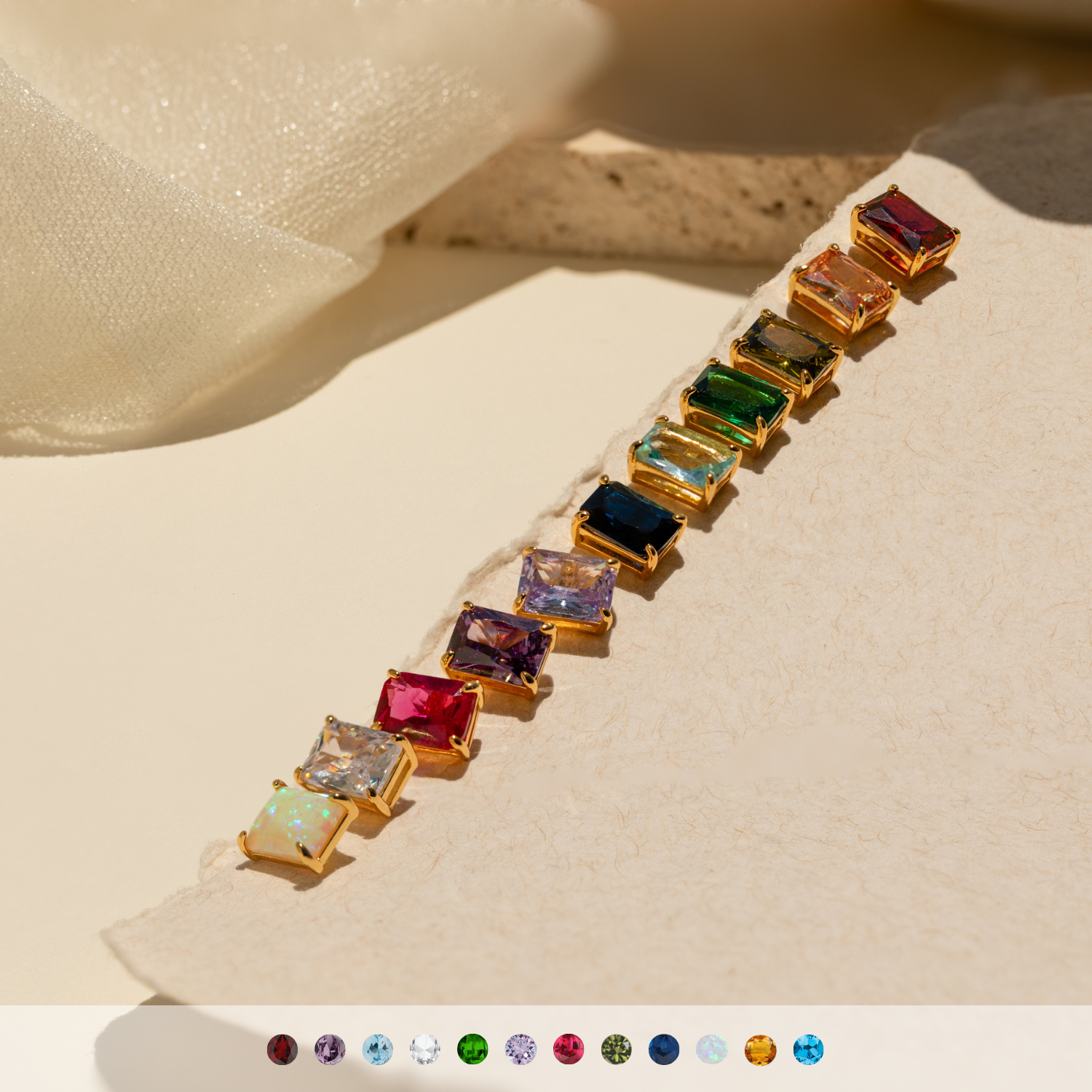 Emerald Birthstone Studs, ideal for personalized gifts, are displayed on a textured beige surface in sunlight.