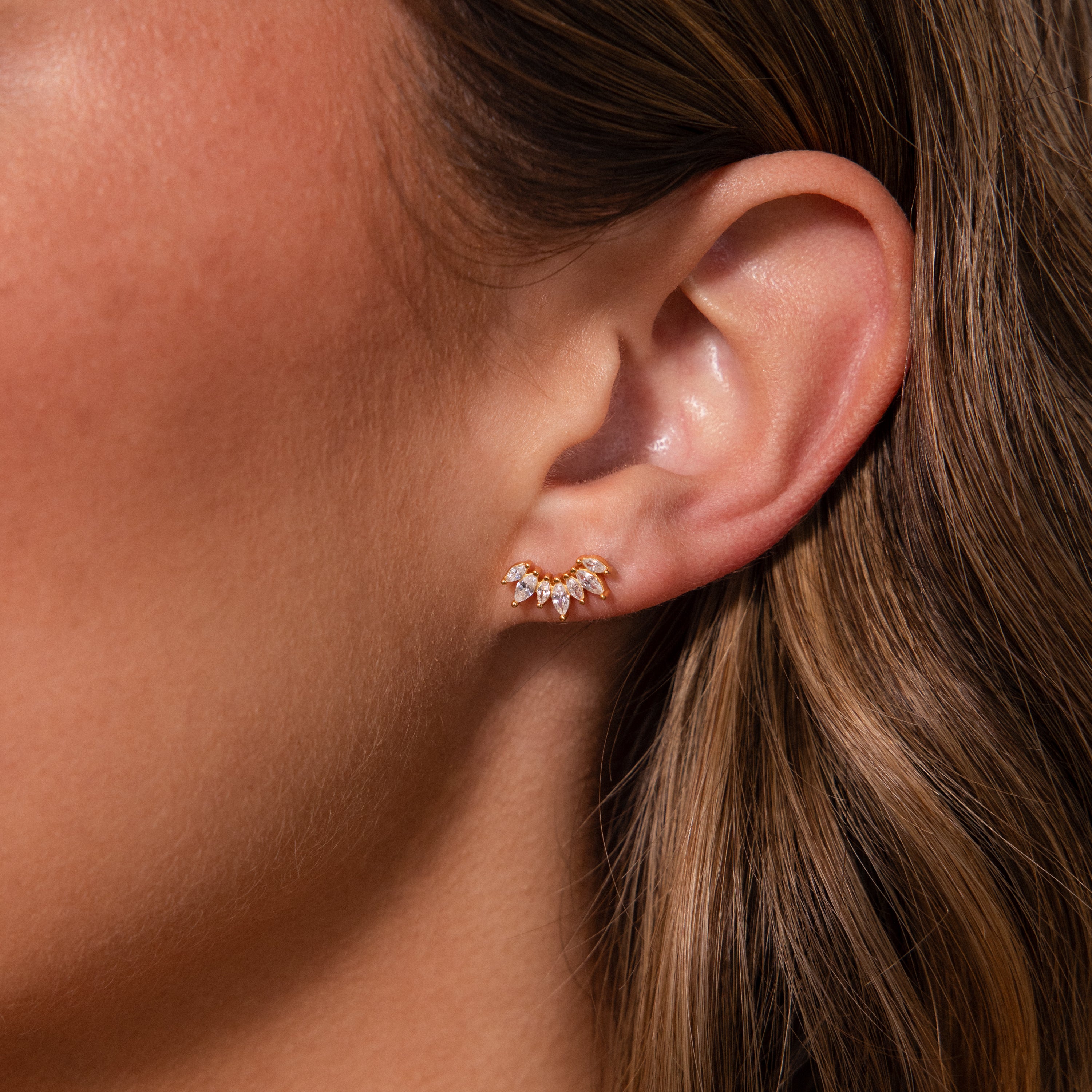 Close-up of a womans ear wearing Marquise Diamond Arc Climbers in 18K Gold, adorned with small marquise stones for a delicate sparkle.