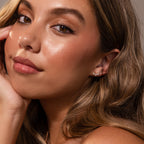 Woman with long wavy hair, glowing skin, and subtle makeup wears Marquise Diamond Arc Climbers in 18K Gold, posing thoughtfully.