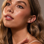 A woman with wavy brown hair and natural makeup looks upward, wearing Blue Opal Prism Studs in 18K Gold, highlighting her preference for elegant iridescent jewelry.