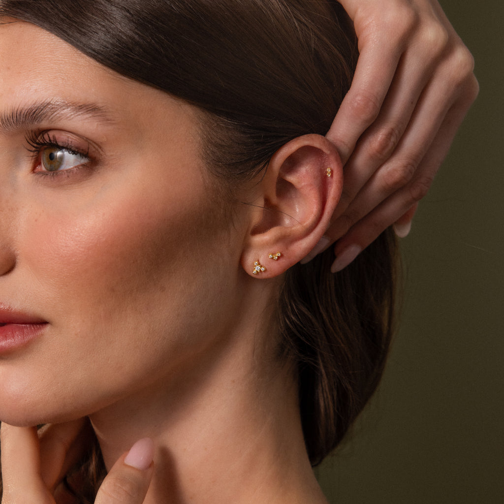 Model wearing a dainty gold crystal flat back earring stack with coordinating cluster studs along the lobe and cartilage.
