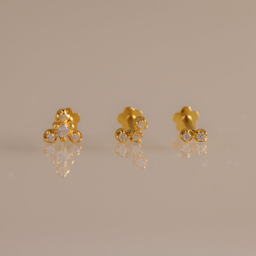 Close up of three gold crystal cluster flat back stud earrings featuring graduated two, three, and four stone designs.