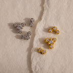 Gold and silver crystal cluster flat back stud earrings in three delicate designs displayed on textured ivory paper