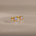 Blue Opal Prism Studs in 18K Gold featuring square blue opals, showcased on a smooth, reflective surface.