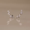 Diamond Starfall Climbers in Silver, featuring marquise and round white gemstones, styled as elegant ear climbers, displayed on a glossy beige surface.
