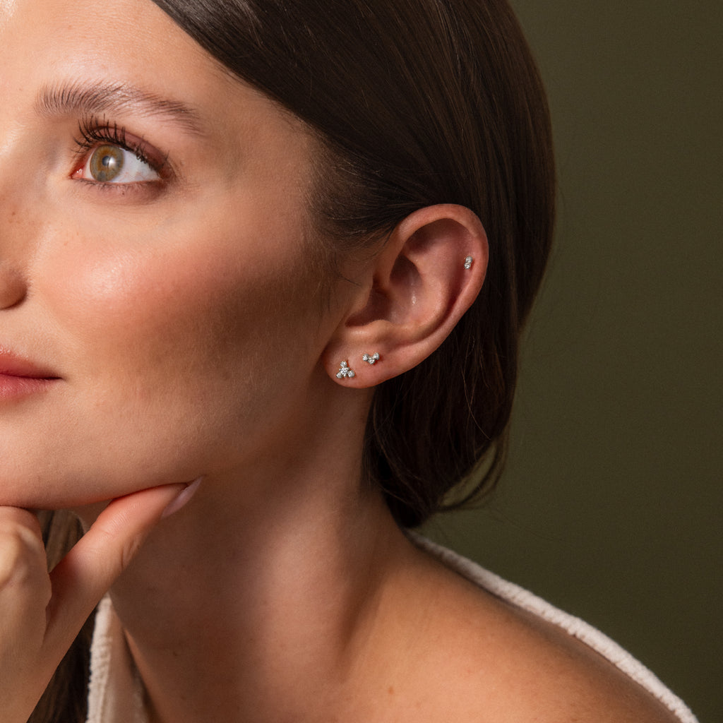 Model wearing a delicate silver crystal flat back earring stack with tiny sparkling cluster studs on the lobe and cartilage.