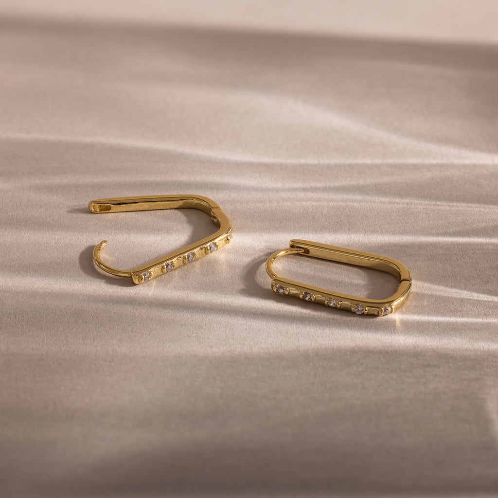 Dainty Pave Link Earrings in 18K Gold with embedded cubic zirconia, displayed on a textured light-colored surface.