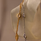The Moonstone Hand Chain Bracelet, featuring gold and silver chains with oval moonstones, is elegantly displayed on a translucent hand-shaped stand for a celestial jewelry touch.