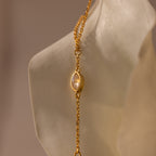 Moonstone Hand Chain Bracelet in 18K Gold featuring an oval moonstone charm, elegantly displayed against a sculpted white background—perfect for fans of celestial-inspired jewelry.