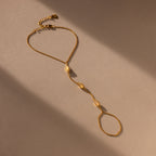 The Moonstone Hand Chain Bracelet features three delicate oval accents and is shown in soft light on a beige surface.