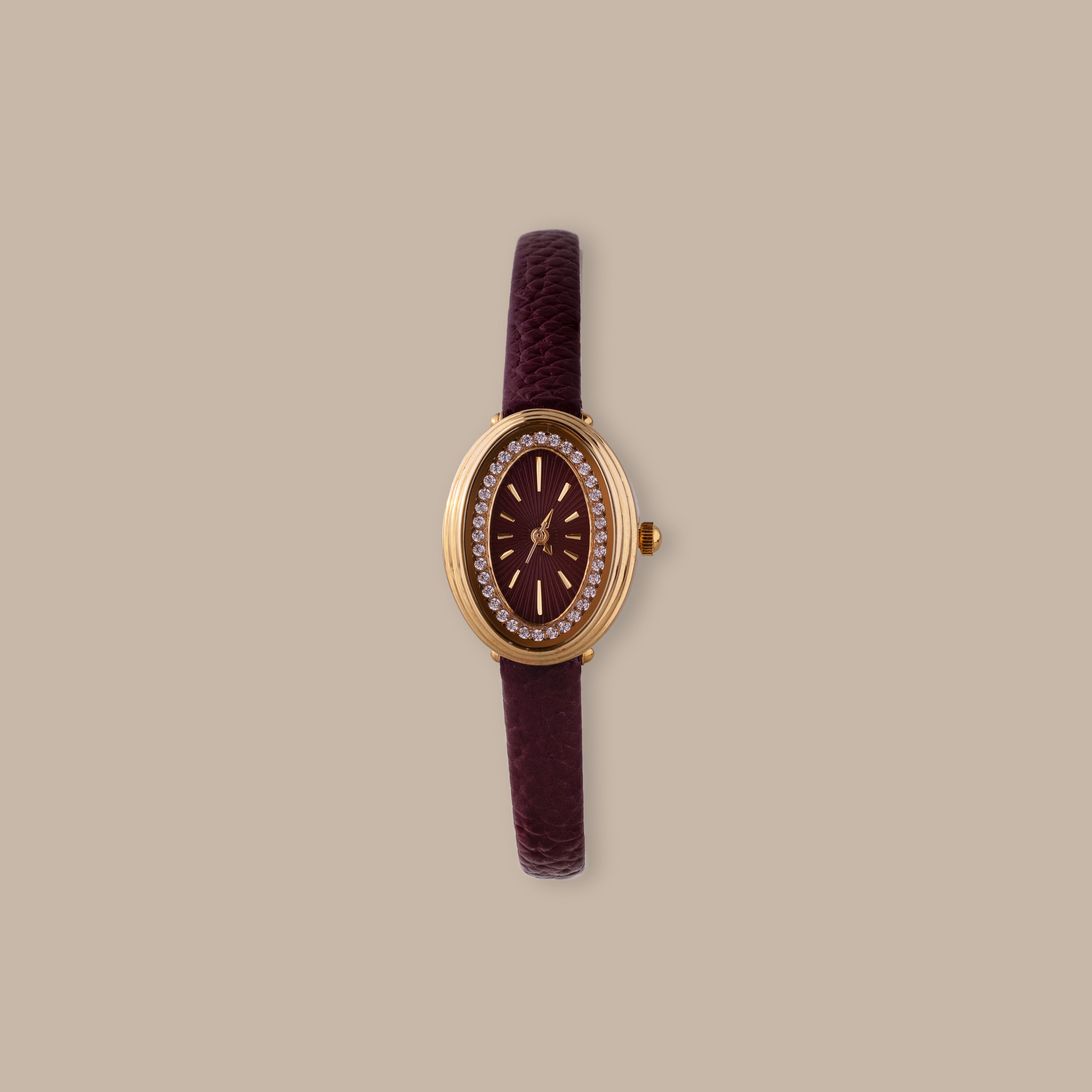 Merlot Strap Timepiece: Gold-tone oval watch with burgundy dial, crystal accents, and textured leather strap.