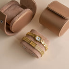 Two additional vintage-style gold watches displayed on a suede watch roll beside matching travel cases.