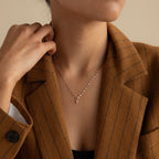 A woman in a brown pinstripe blazer wears the Dainty Marquise Pendant Necklace in Silver with a mirror twist chain, her hand resting gently near her neck.
