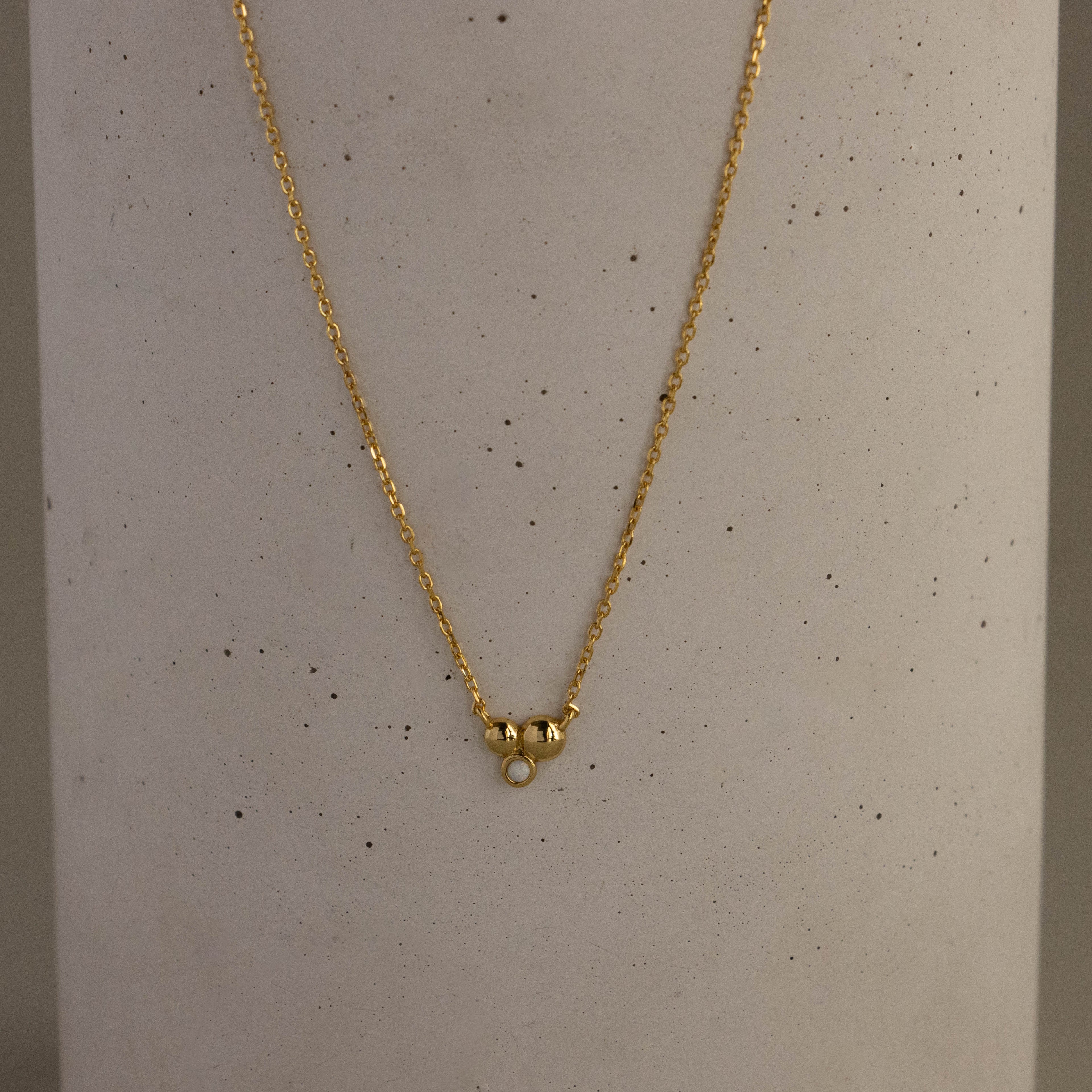 Round Trio Opal Charm Necklace featuring a small round opal pendant, shown against a light gray speckled background.