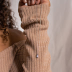 A person in a beige ribbed sweater holds the Sage Diamond Necklace in Silver, its delicate pendant gleaming with timeless elegance.