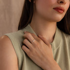 Close-up of a dainty silver double initial ring featuring bubble letters H and G, worn on hand resting near collarbone.