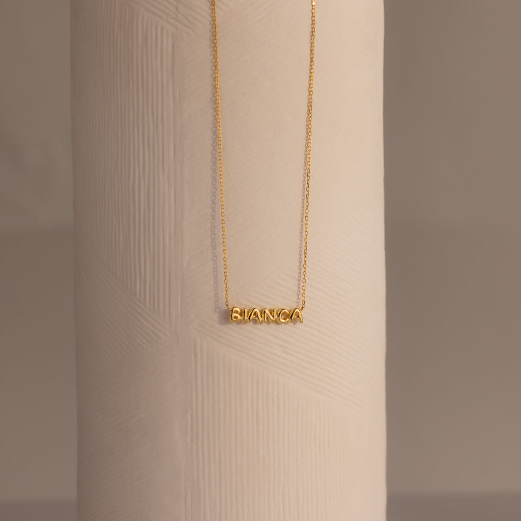 Tiny Bubble Name Necklace featuring BIANCA on a textured white cylinder—a personalized piece that adds a unique touch.