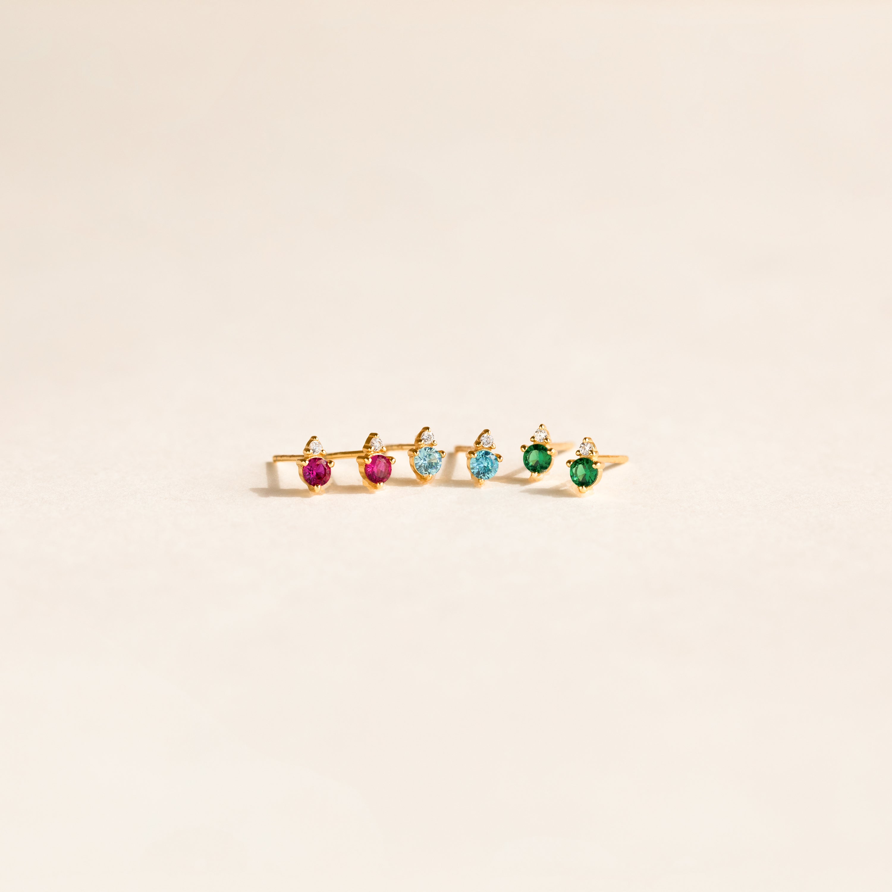 Five gold rings with pink, blue, and green gemstones are displayed in a row on a light background—perfect to pair with your favorite Raindrop Aquamarine Studs or dainty earrings.