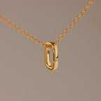 Multipurpose Charm Hoop Clasp Set in 18K Gold features a gold chain necklace with an oval pendant and a versatile charm hoop clasp, ideal for bracelet stacking, shown against a plain beige background.