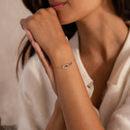 Woman wearing a delicate silver chain bracelet featuring an interlocking link pendant with one pave-set link.