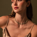 A woman in a satin dress wears the Tiny Jade Choker Necklace in 18K Gold, gazing to the side against a neutral backdrop.