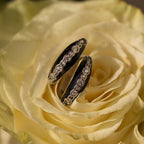 Two Noir Pave Dome Hoops in Silver with diamond details rest on pale yellow rose petals, creating a stunning statement earring pair.