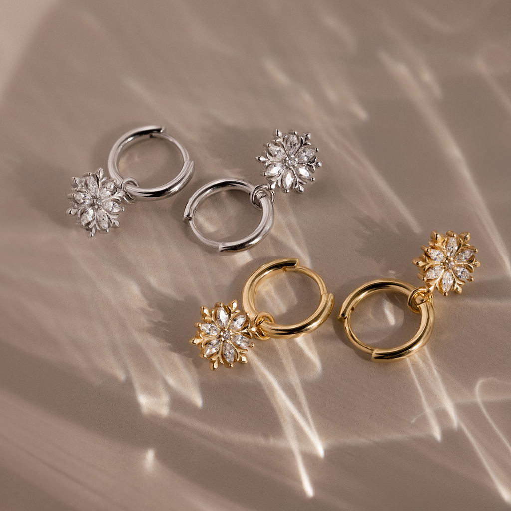 Flatlay of 2 pairs of our Diamond Poinsettia Hoops in Silver and Gold