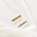 Two gold and silver bar necklaces with engraved text on a white background