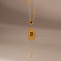The Topaz Crystal Necklace showcases a gold teardrop pendant with a square detail on a simple gold chain—ideal for layering or wearing alone as a distinctive Birthstone Crystal Necklace.