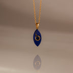 The Sapphire Crystal Necklace features a gold chain and a blue, marquise-shaped pendant with a gold spiral design, making it a perfect Birthstone Crystal Necklace for any occasion.