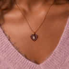 A Pink Tourmaline Crystal Necklace is worn over a pink fuzzy V-neck sweater.