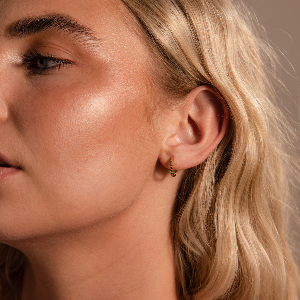 Close-up of a woman with blonde hair wearing elegant Inside Out Birthstone Huggies, highlighting her clear glowing skin.
