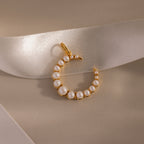 The Pearl Moon Charm in 18K Gold is a celestial necklace with pearls, beautifully displayed on a beige background and satin ribbon—a truly stunning jewelry piece.