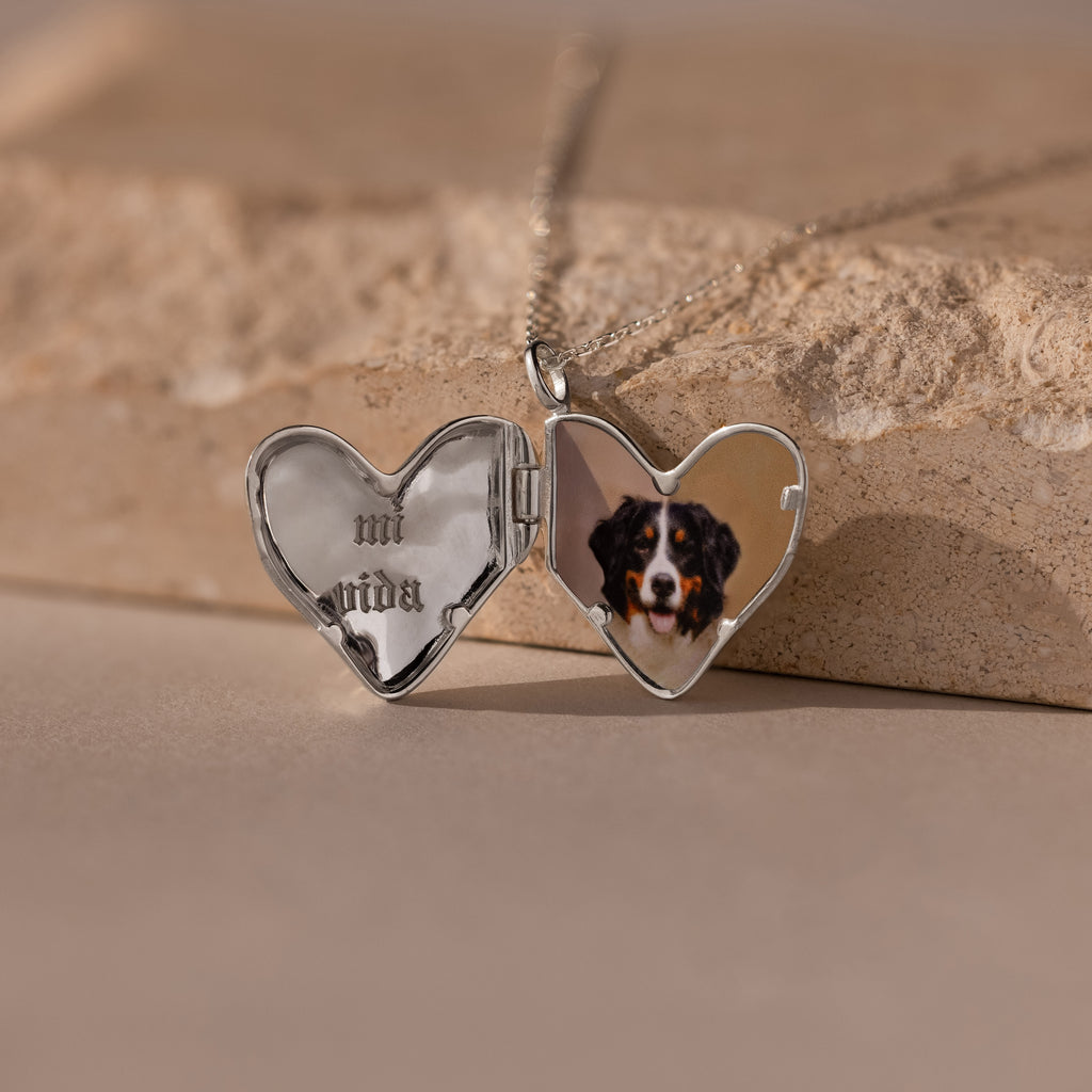 The Organic Heart Locket Necklace opens to reveal "mi vida" engraved on one side and a dog photo on the other, making it a cherished keepsake to hold special memories.
