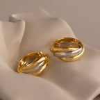Intertwined Mixed Metal Hoops showcased on a soft, light-colored fabric background.