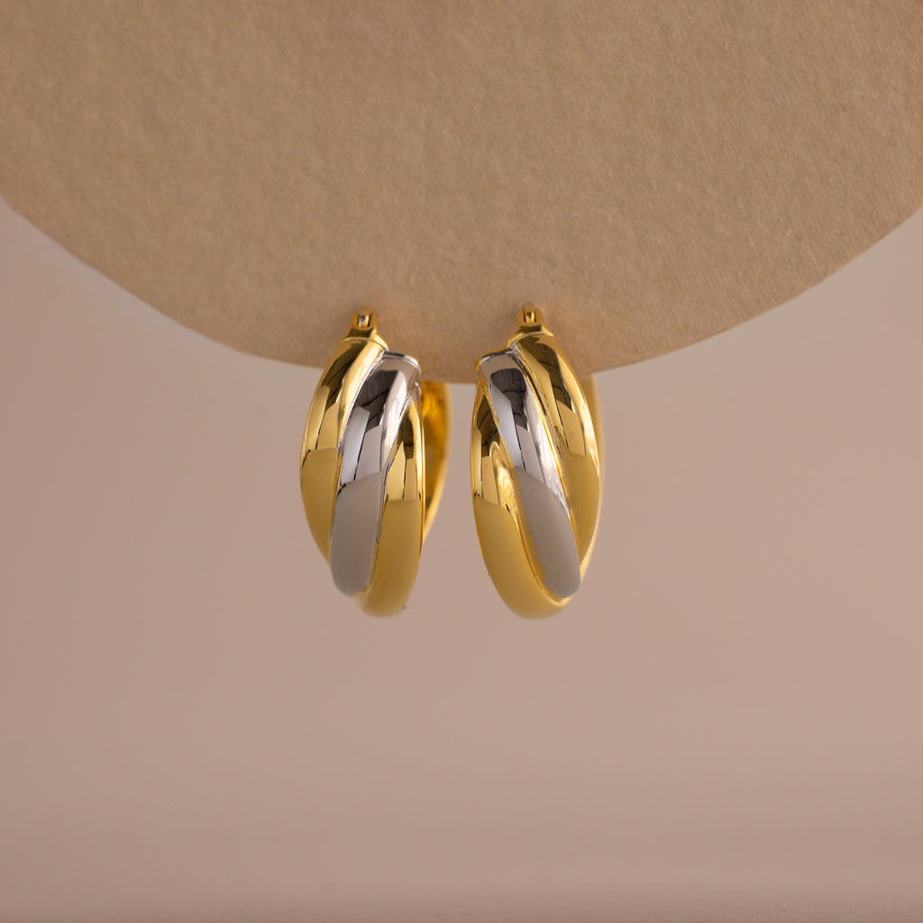 The Intertwined Mixed Metal Hoops feature gold and silver twisted hoops, creating a striking two-tone look against a neutral backdrop.