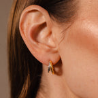 Close-up of a woman's ear wearing Mixed Metal Duo Hoops, showing small gold and silver earrings with brown hair partially visible.