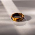 Experience earthy elegance with the Skinny Tiger's Eye Ring, featuring a rich brown gemstone set on a light gray surface in soft sunlight. Ideal as a stacking ring for a refined, natural look.