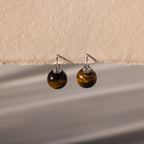 Tiger's Eye Dome Drop Earrings with silver hooks, featuring natural stone jewelry, displayed on a textured beige background.