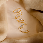Five delicate gold rings from Mystery Jewelry with small gemstones arranged on beige fabric, each piece showcasing whimsical charm and a variety of elegant, unique styles.