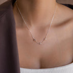 Model wears silver bubble letter necklace spelling “MDH”.