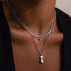 Layered silver necklaces with a pendant on a woman wearing a black top.