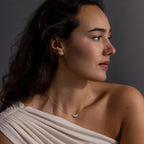 A woman with long dark hair in an off-shoulder white top showcases the Marquise Diamond Jewelry Set, featuring a diamond necklace and matching earrings—an elegant choice for wedding jewelry.