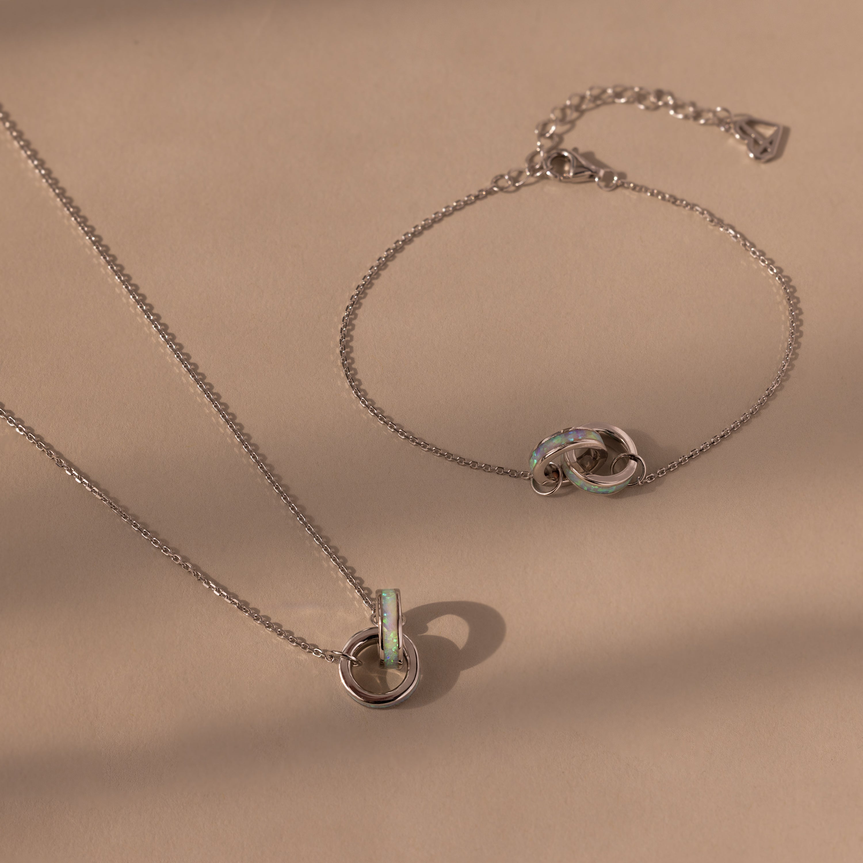 Interlocking Opal Inlay Necklace and Bracelet Set with elegant jewelry pendants displayed on a beige background.