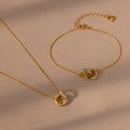 The Interlocking Opal Inlay Necklace and Bracelet Set in 18K Gold features delicate chains and interlocking rings, displayed on a beige background.