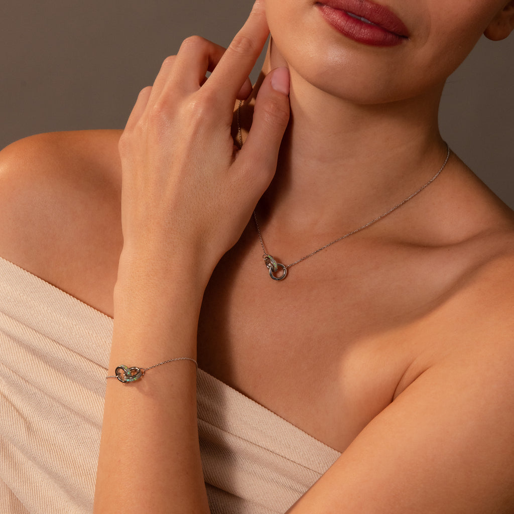 Woman wearing an off-shoulder top, styled with the Interlocking Opal Inlay Necklace and Bracelet Set in Silver, featuring delicate linked circle pendants.