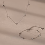 Heart Station Necklace & Bracelet Set in Sterling Silver with small heart charms displayed on a beige surface.